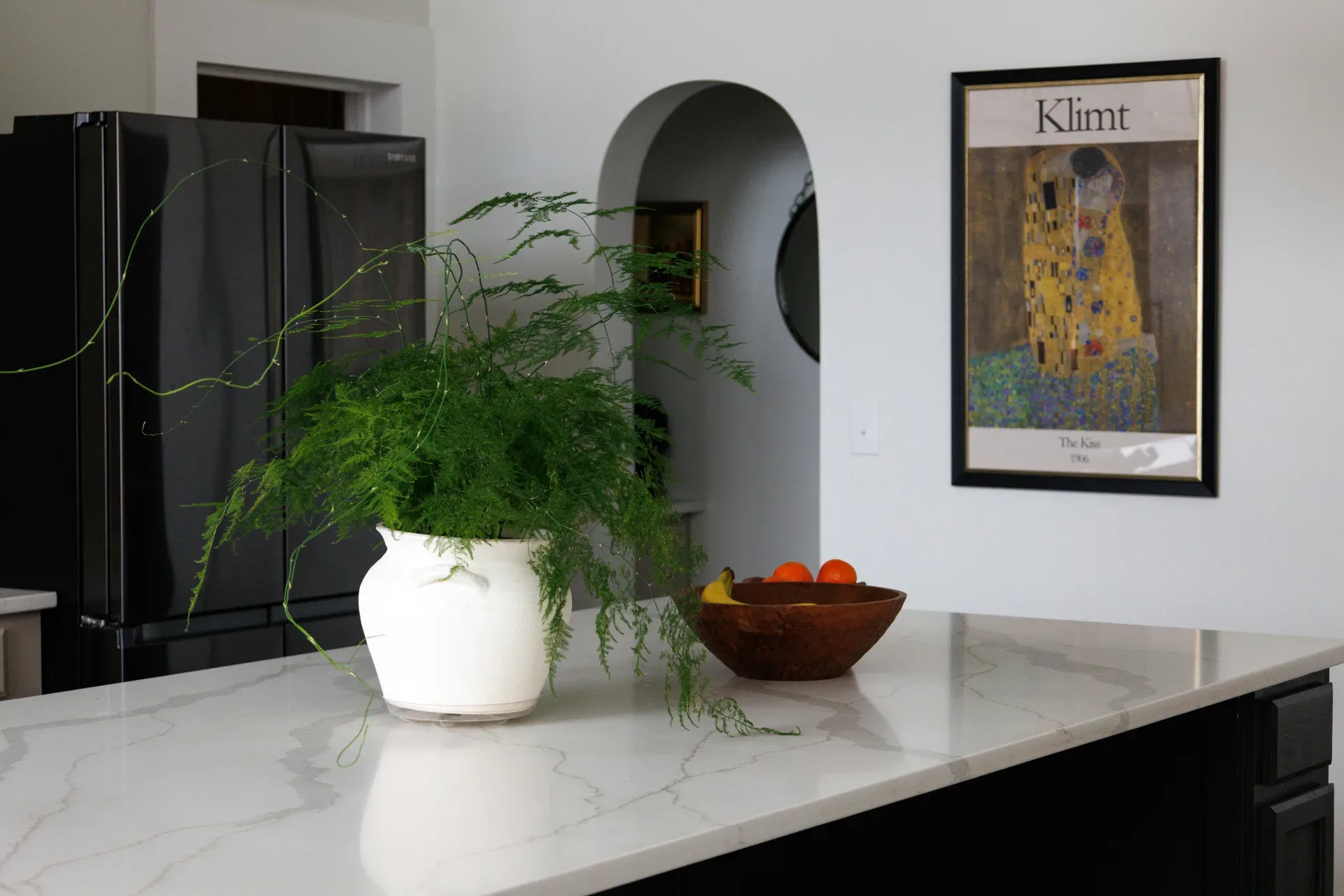 A kitchen island with a plant and fruit bowl.