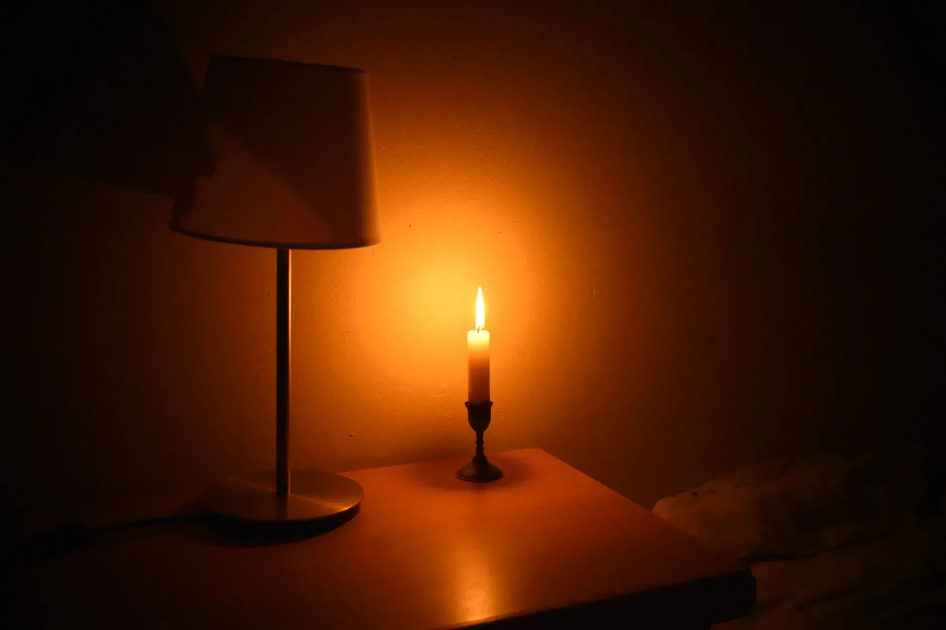 A serene bedside image highlighting a lit candle casting warm light in a quiet room.