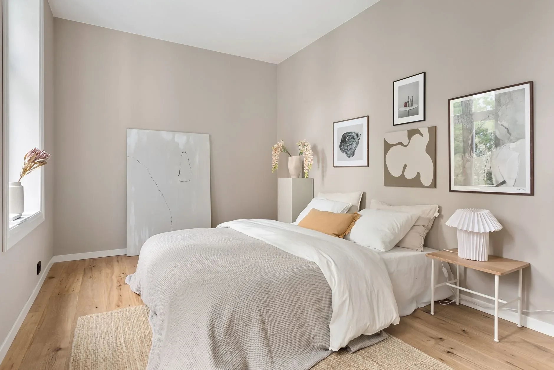 A serene minimalist bedroom with neutral tones, modern art, and soft bedding.