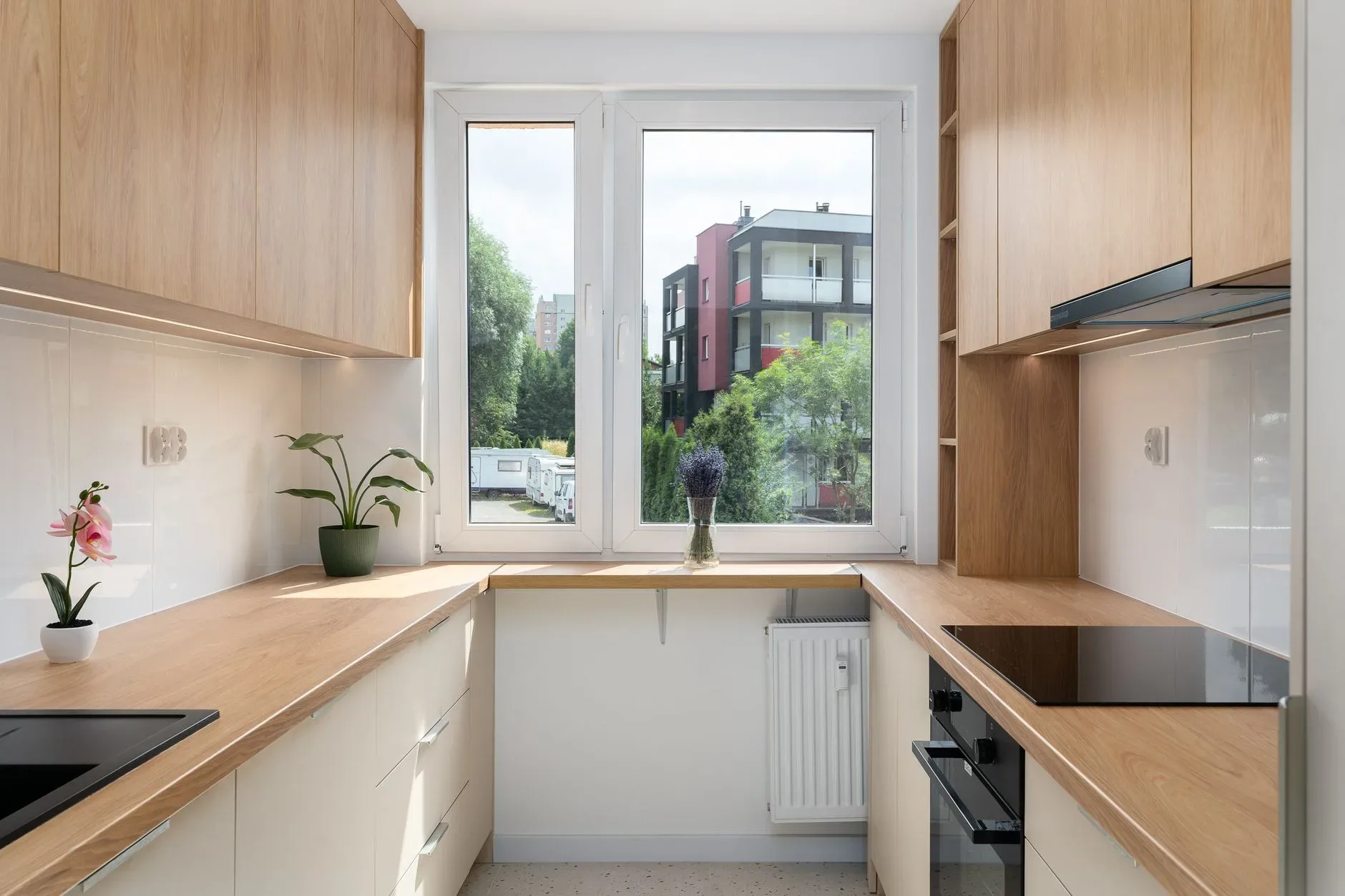 A sleek and contemporary kitchen with natural wood accents and a city view through the large window.