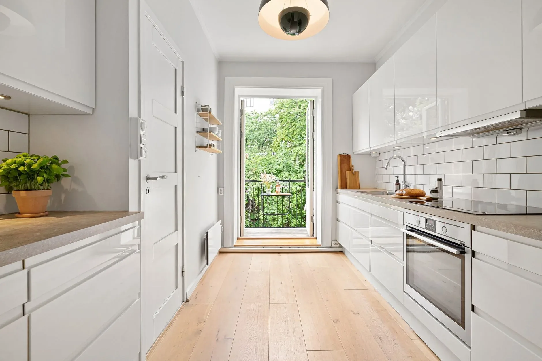 A sleek modern kitchen with white cabinets and access to a small balcony.