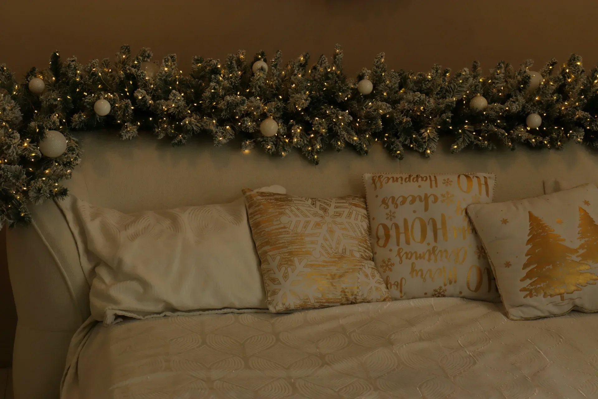 Christmas garland with lights and ornaments above bed