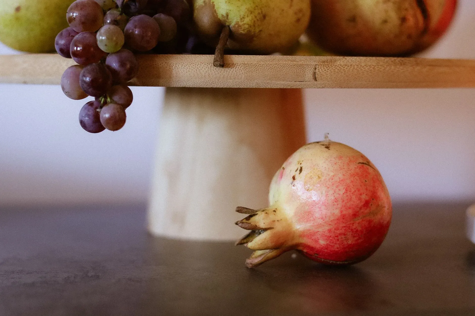 Colorful arrangement of ripe pomegranate and grapes on a wooden stand for a fresh, rustic look.