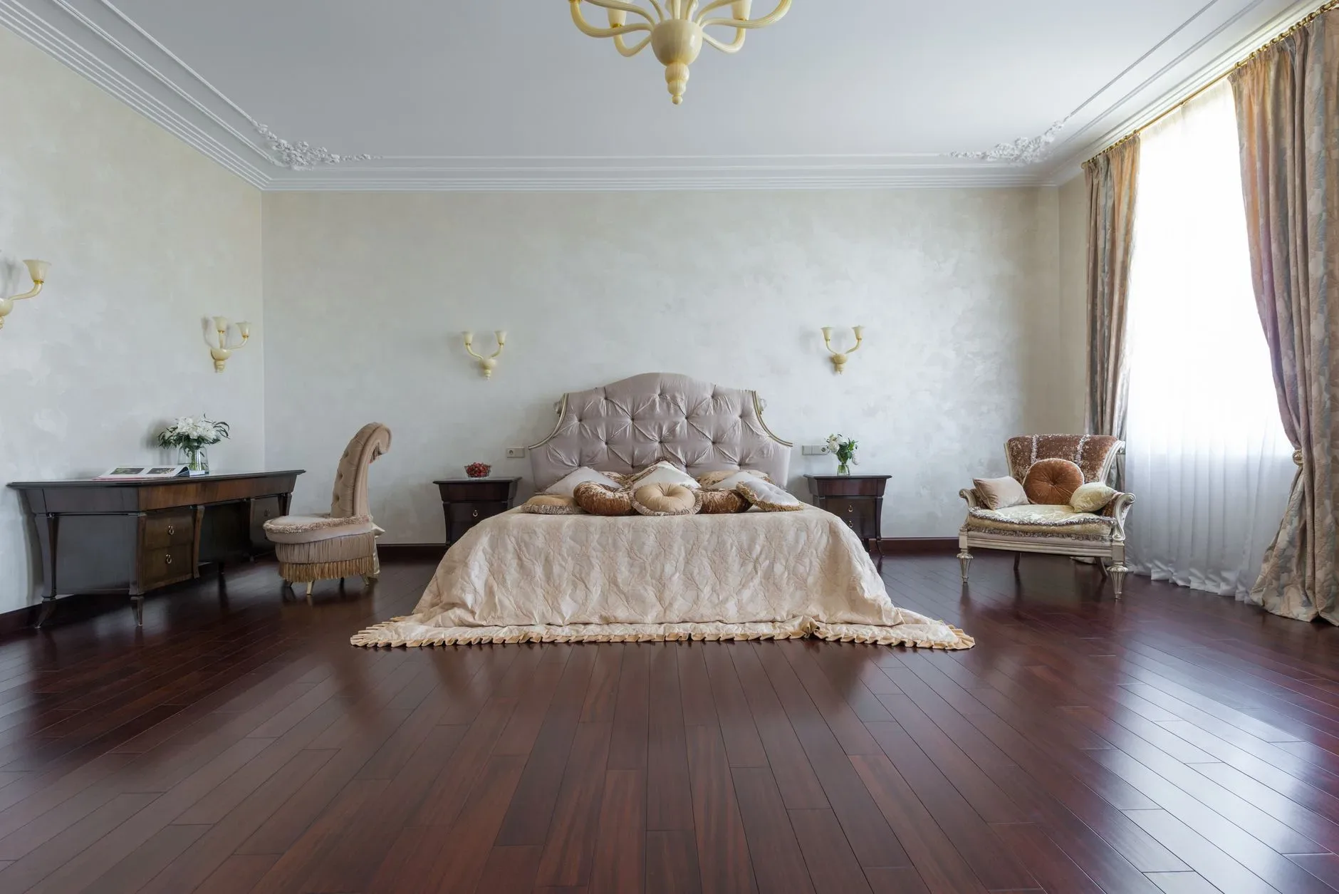 Interior of spacious bedroom with large comfortable bed decorated with soft pillows near armchairs in daylight