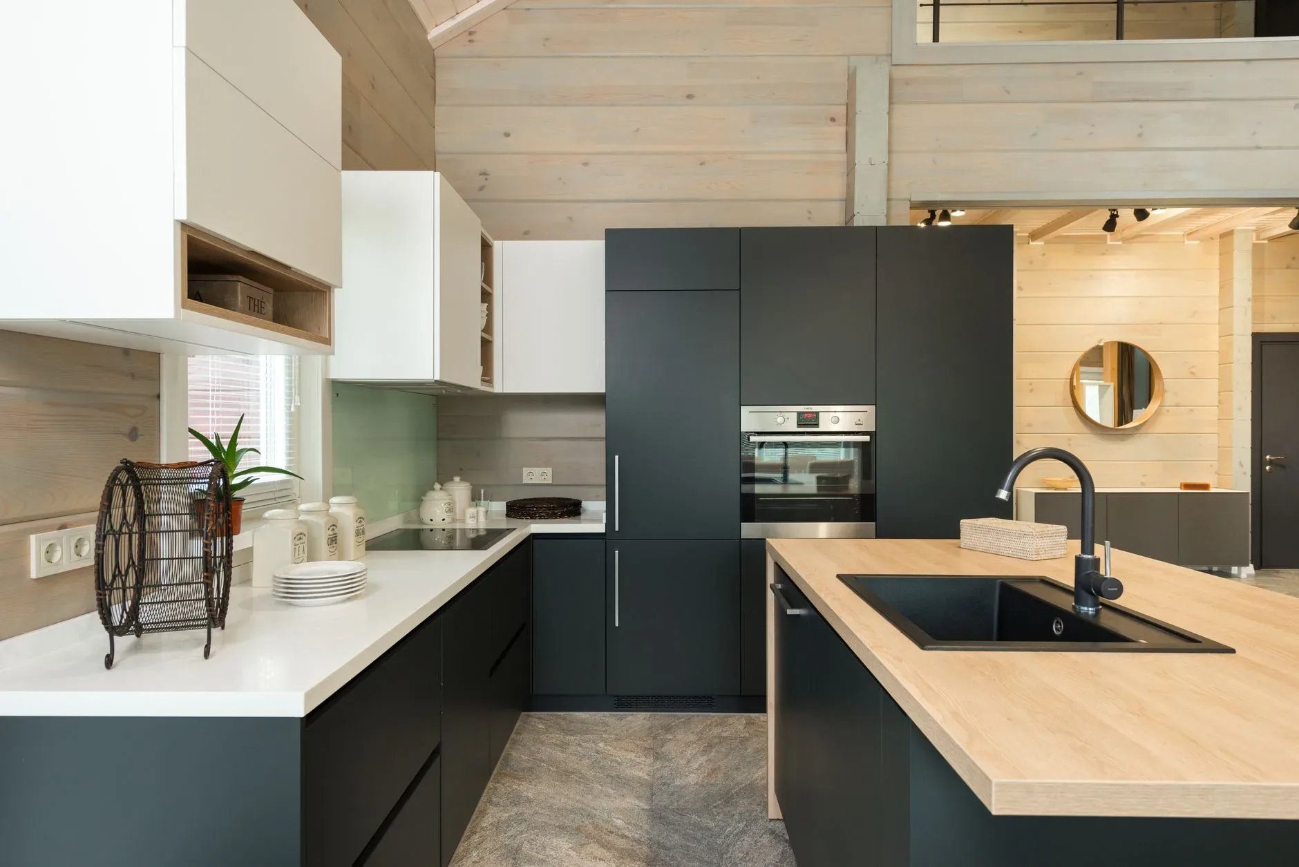 Interior of stylish kitchen with minimalist black and white cabinets built in oven and stove with sink in counter