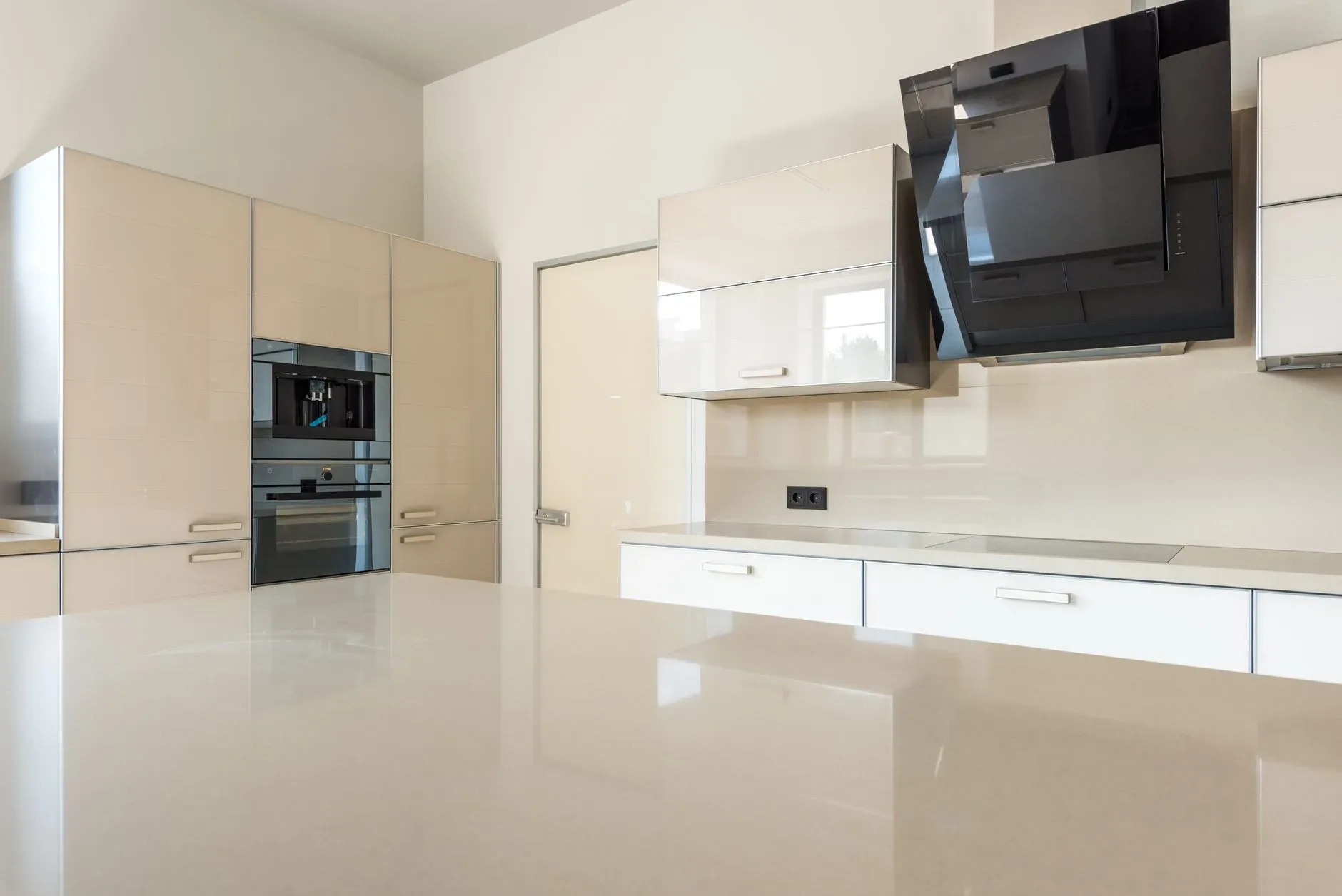 Sleek and spacious modern kitchen design featuring glossy cabinets and high-end appliances.