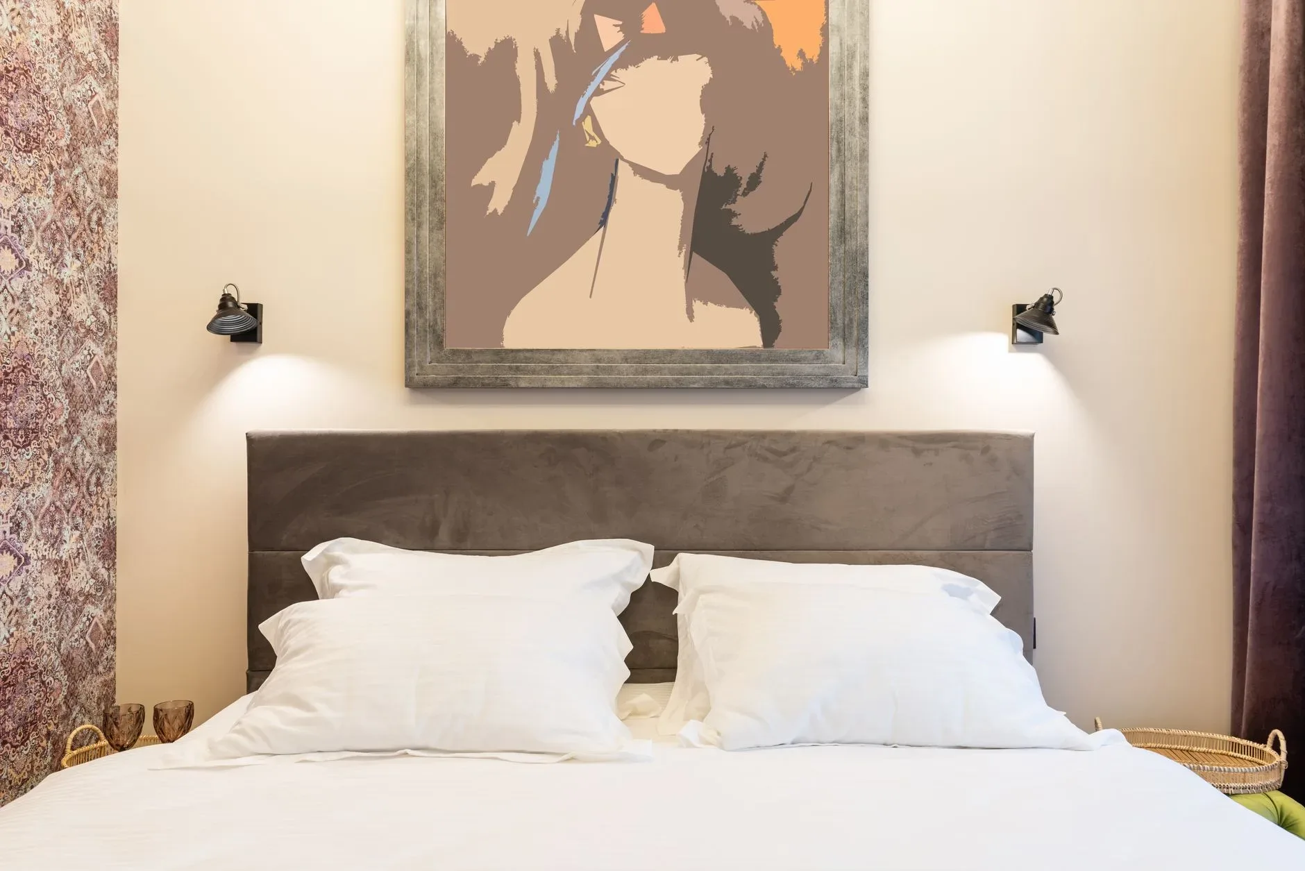 Soft pillows on bed against artwork on wall with shiny lamps and ornament in house