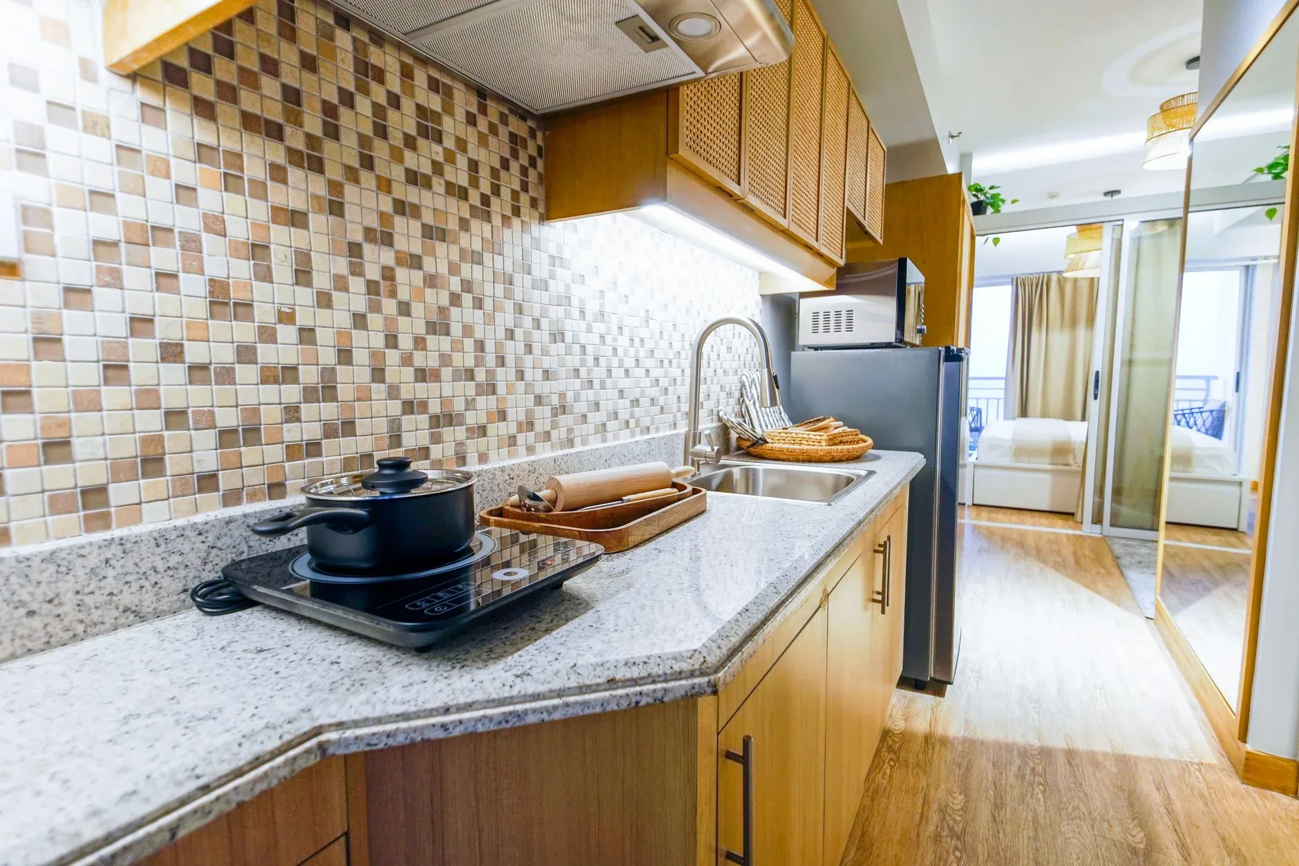 Spacious modern kitchen with induction cooktop, granite countertops, and wooden cabinets in a bright apartment.